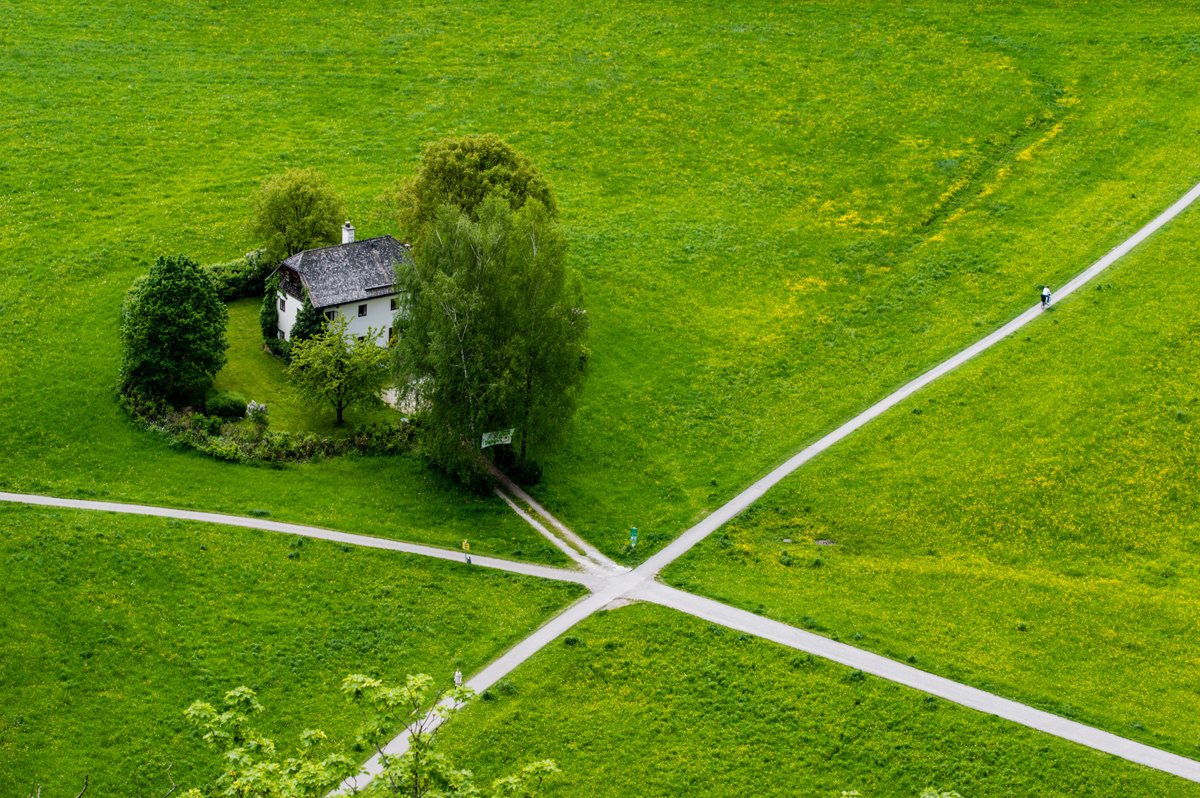 house in a green field with several pathways crossing in front
